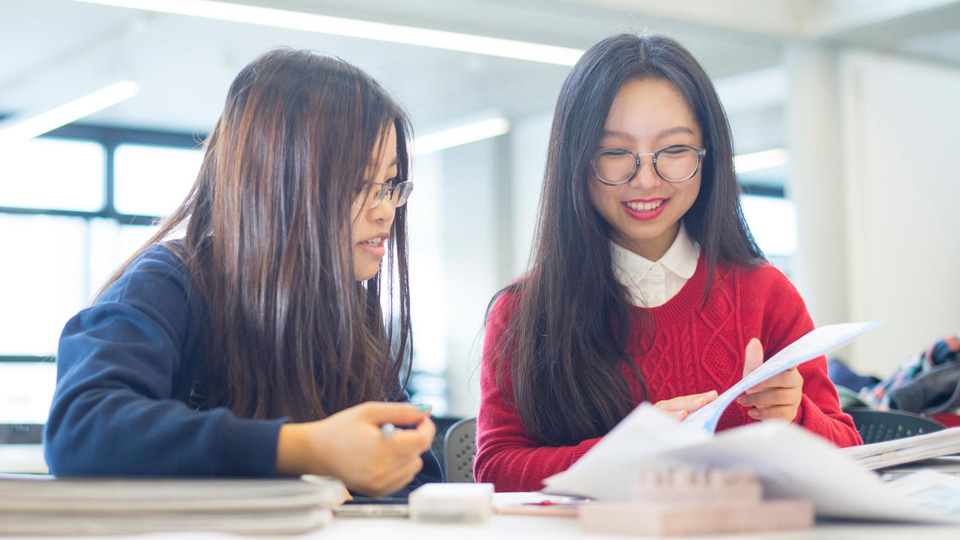 Two students smiling and looking at their work