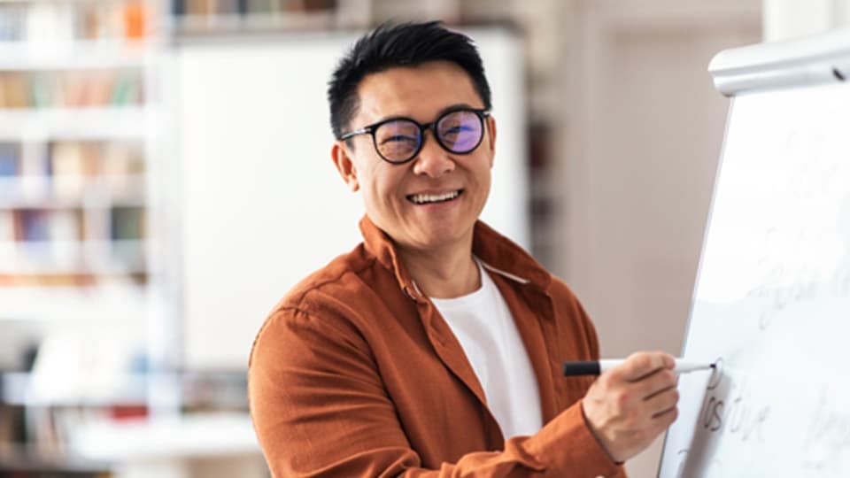A japanese man writing on a whiteboard