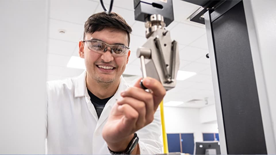 image of male student smiling working in lab