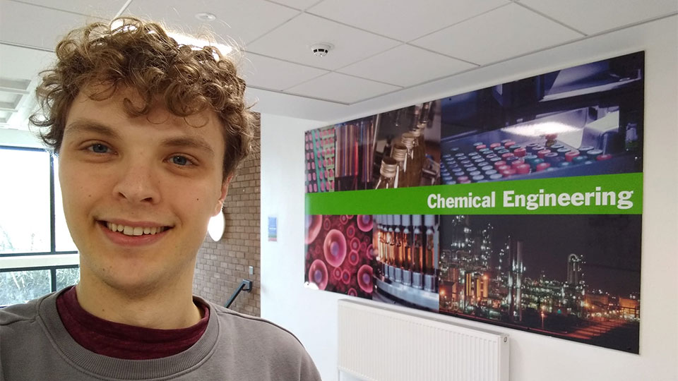 Johannes smiling in front of Chemical Engineering board