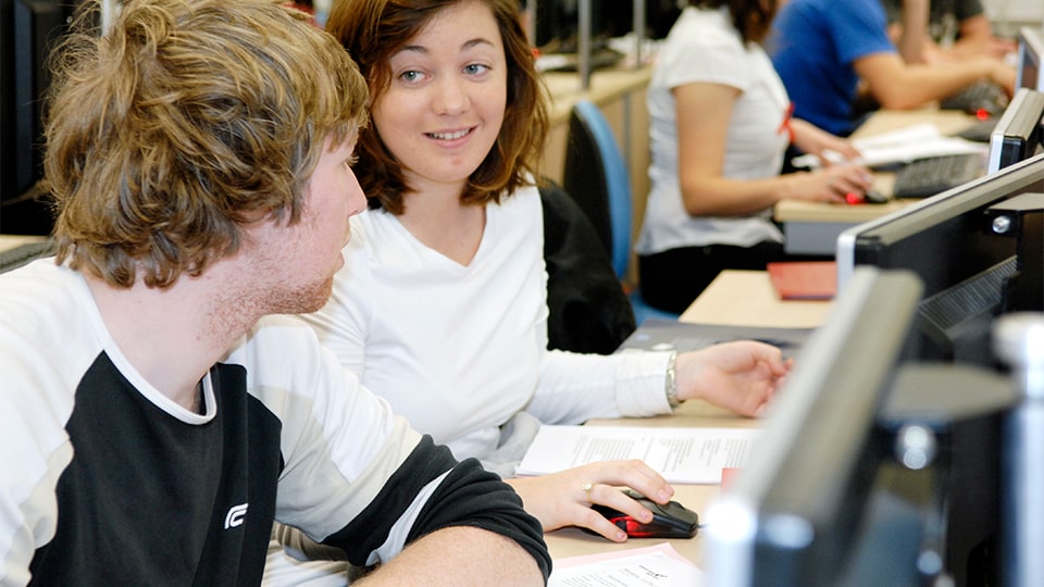 two students sitting at a desk talking
