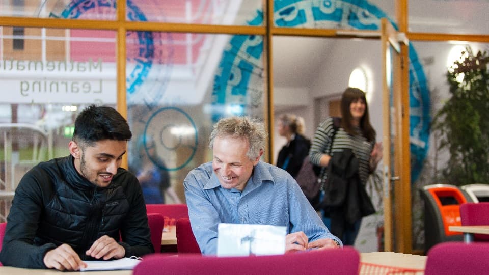 two people sitting at a desk looking at papers