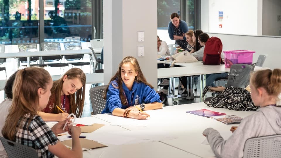 five students sitting around a desk working