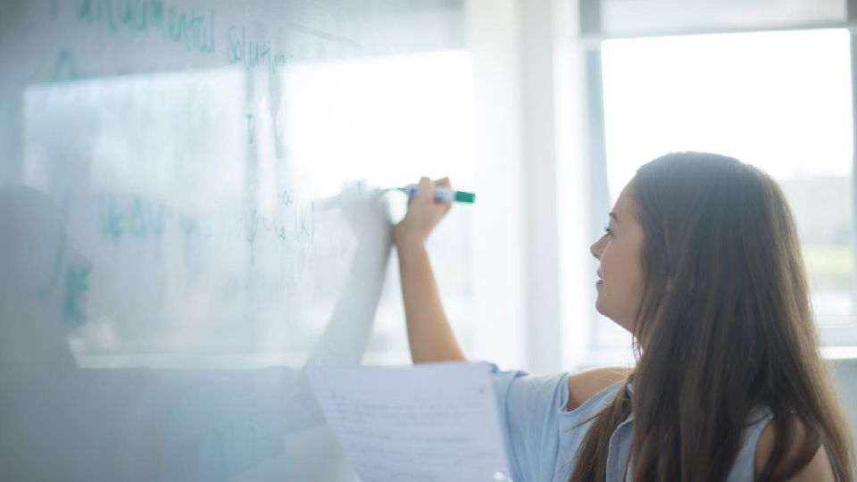 a woman writing on a white board