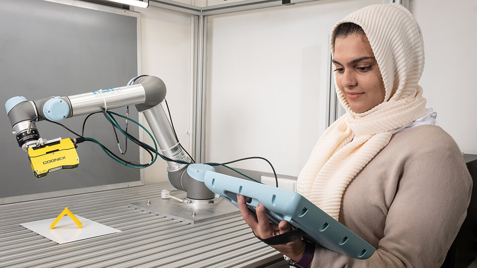 Image of Electronic and Electrical Engineering student, Maryam in the lab looking at equipment. 