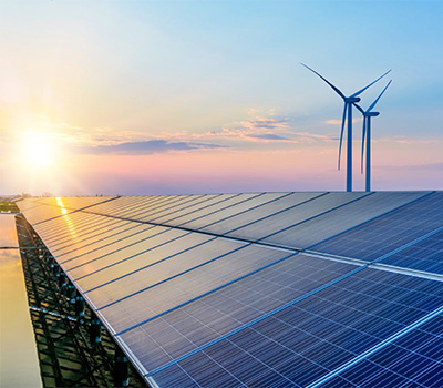 Wind turbines and solar panels whilst the sun is setting.