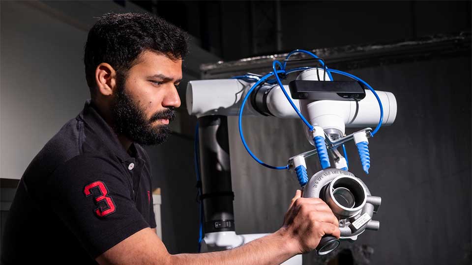 An academic touching and observing a piece of equipment in a lab