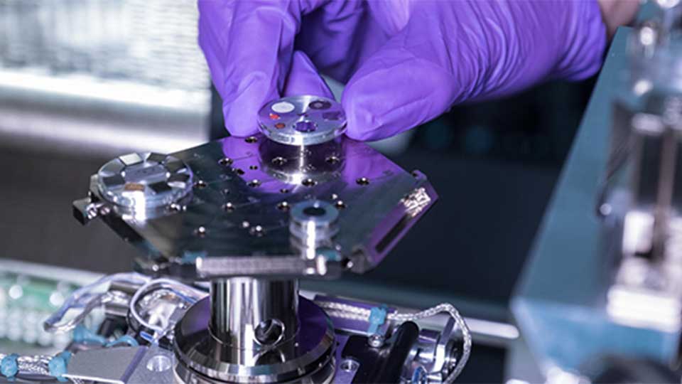 Extreme close-up of a human hand wearing a protective glove touching a piece of metal equipment.
