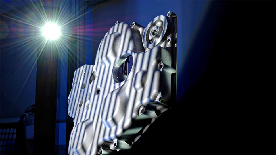 Close-up of a bright light source in a lab shining on a piece of metal equipment.