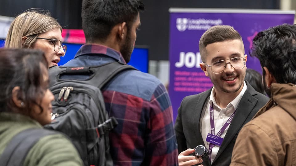 Loughborough University staff member talking to students in careers fair