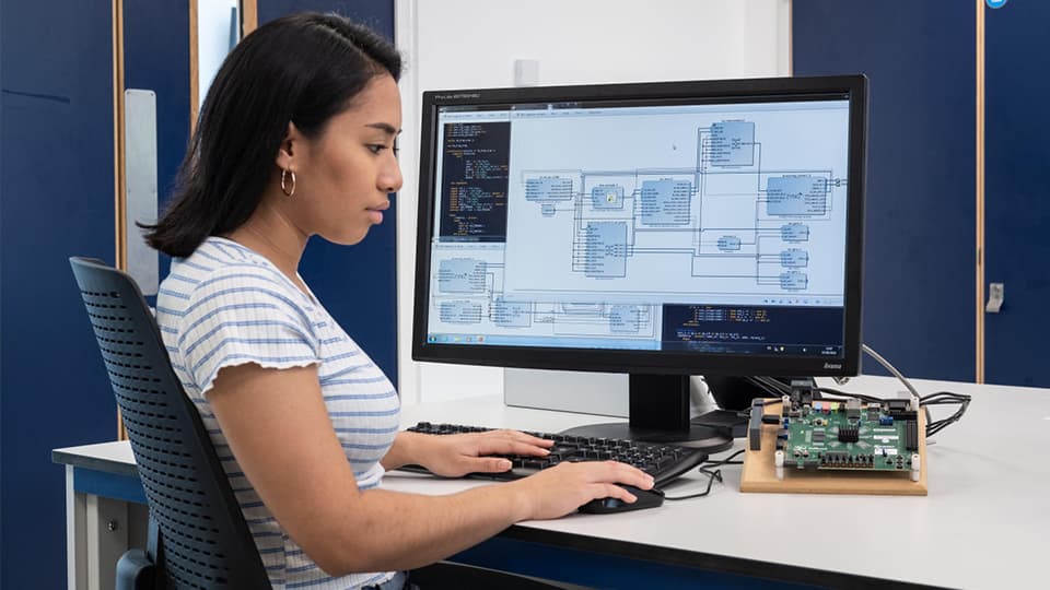 Student sat at a computer with engineering information on display