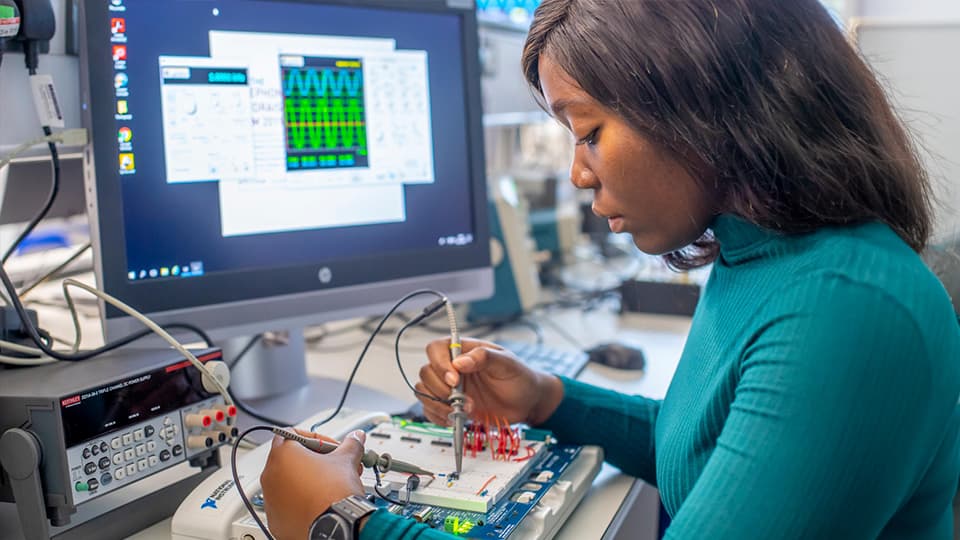 Student sat at a computer with engineering information on display
