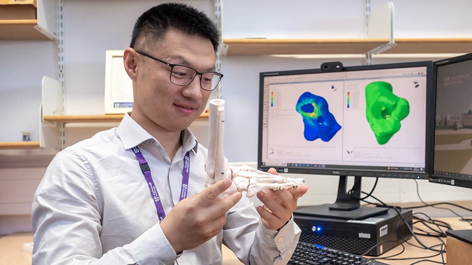 Student sat next to a computer with a model of a foot