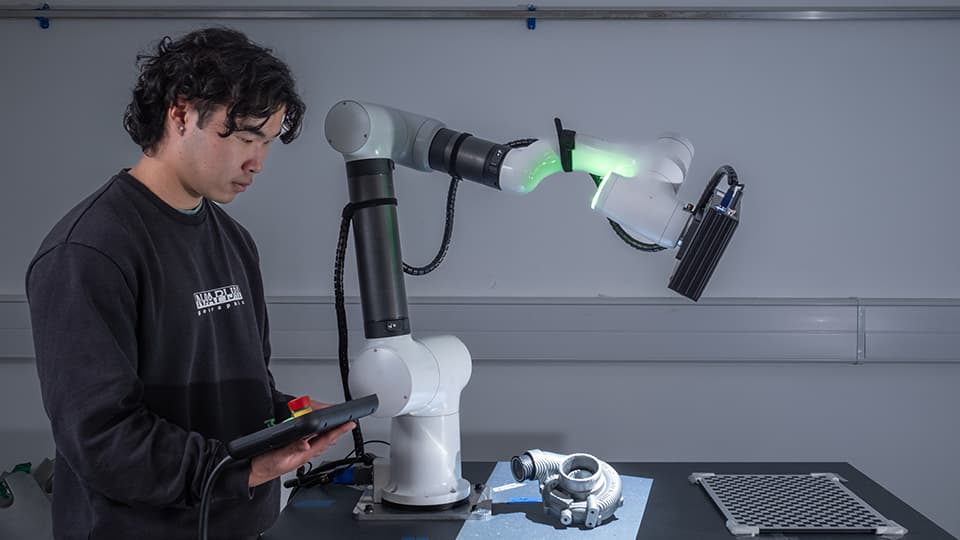 Student in an engineering lab with robotic arm