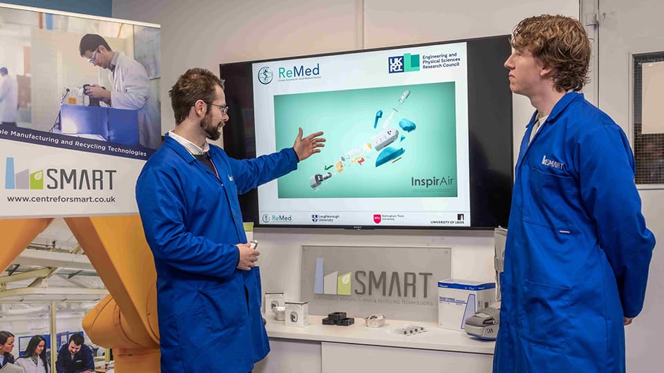 Two students in engineering lab looking at a TV screen