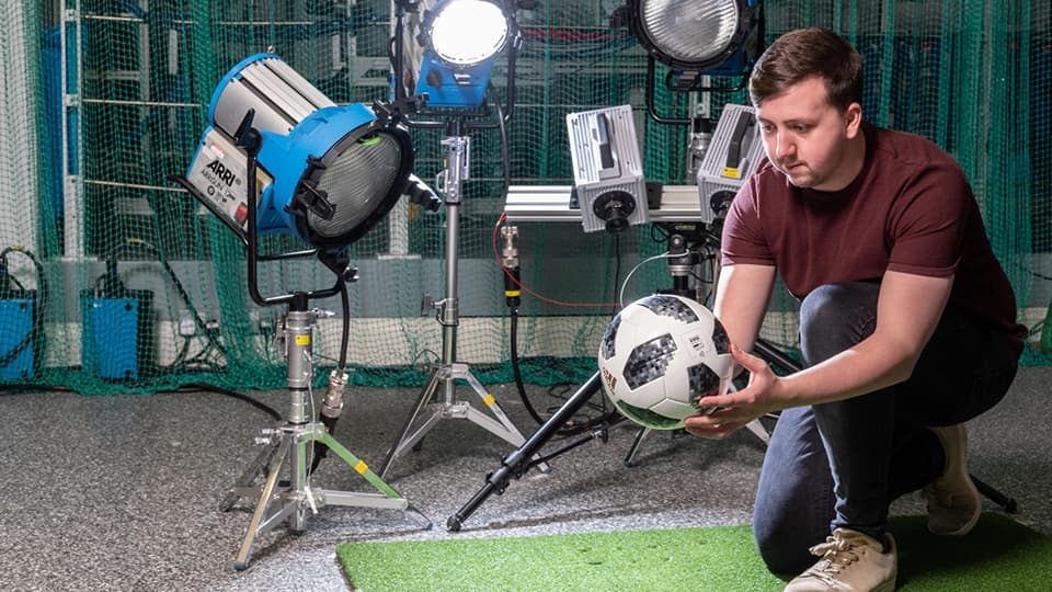 Student in sports engineering lab testing a football
