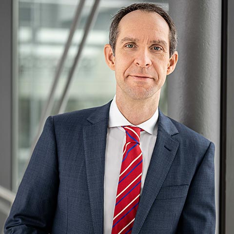 Steffen in suit stood next to glass window