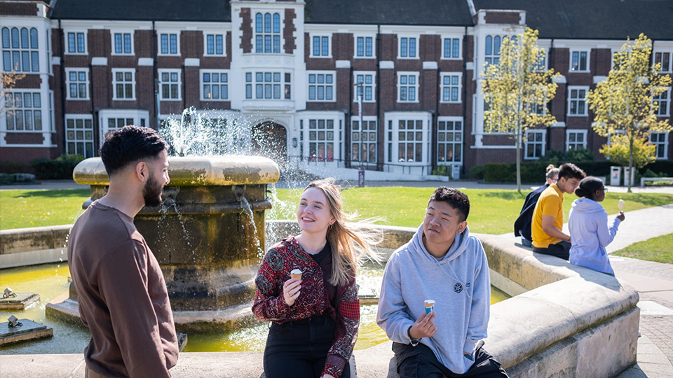 Student sat by fountain by Hazlerigg Building at Loughborough University