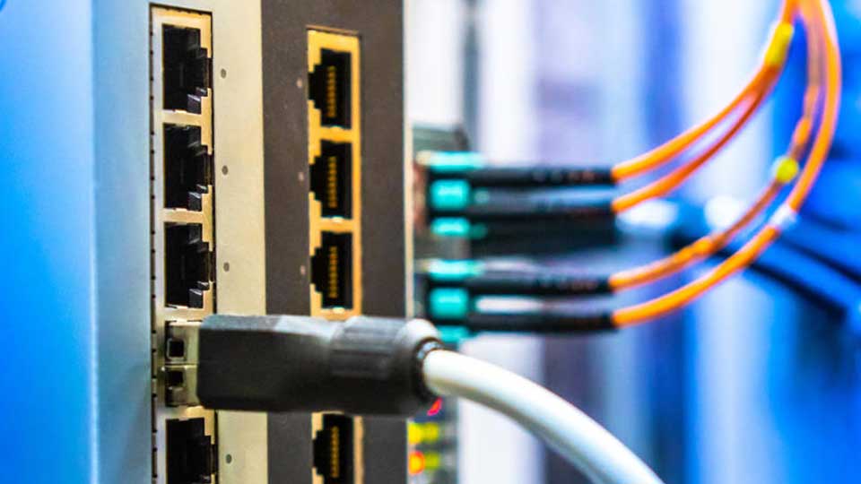 Close up of an electric circuit where orange and grey wires are entering electronic ports.