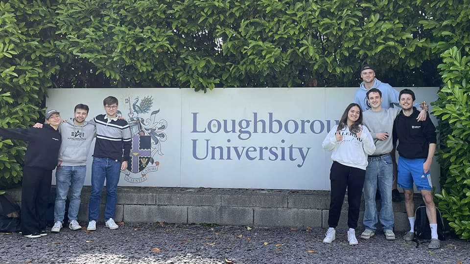 Adam stood by a Loughborough University sign with his friends