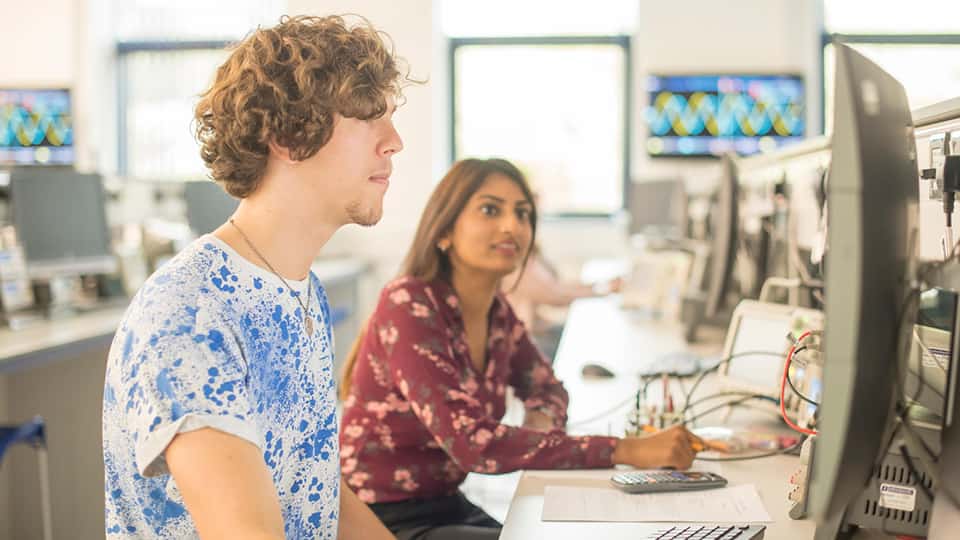 Two students on computers in an engineering lab