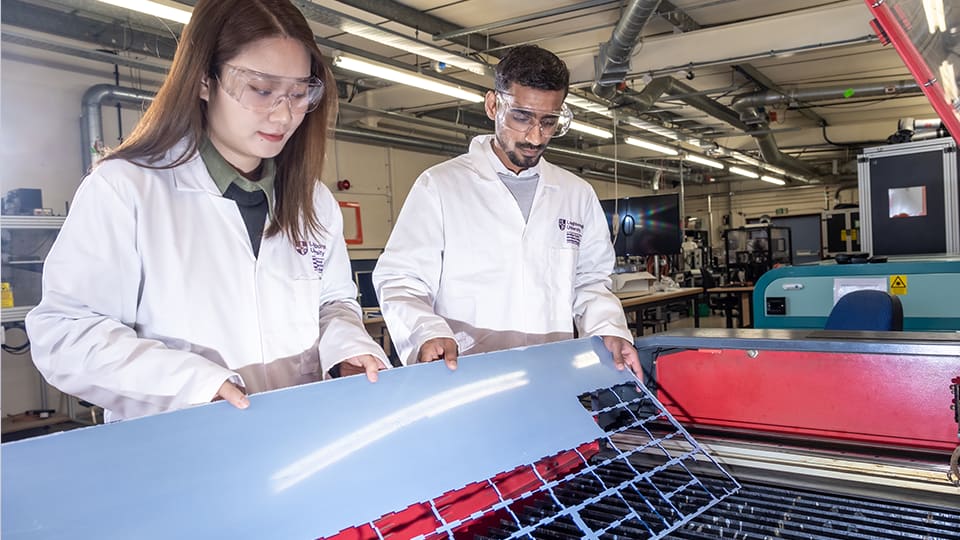 Two students in an engineering lab working with equipment