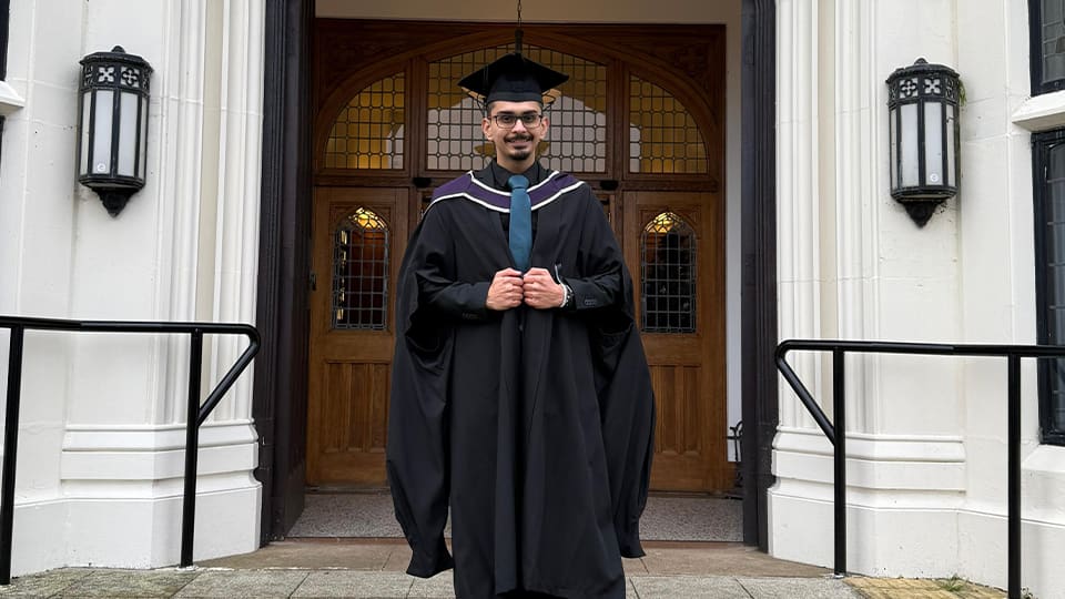 Yashesh outside university building in his graduation gown