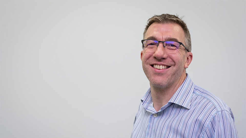 Headshot of Jon, smiling and looking directly at the camera.