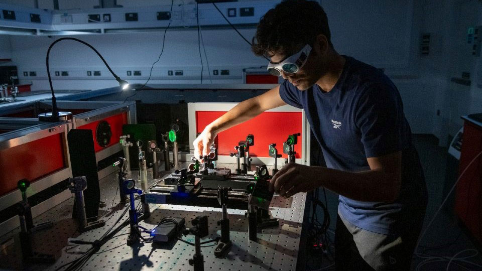 a student in a dark room using photonics lab equipment