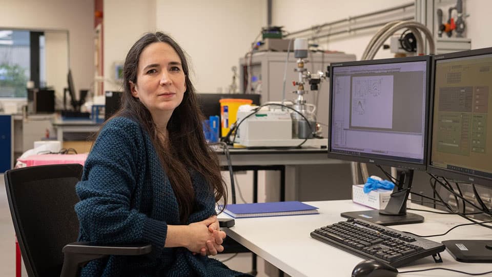 Kelly Morrison sitting at a computer desk in a laboratory.