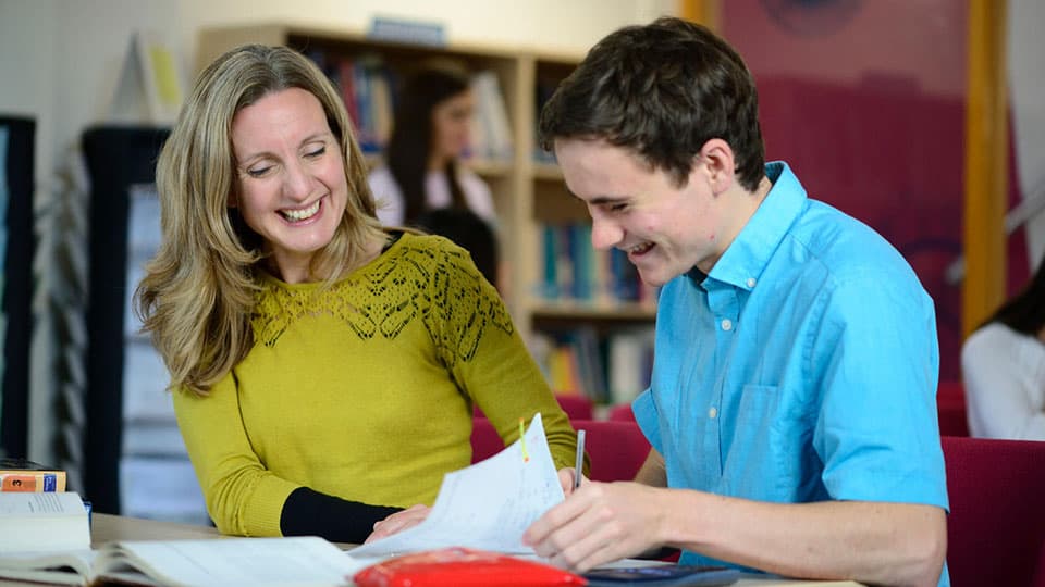 Lara Alcock of the Mathematics Learning Support Centre sitting down with a student to help with their work.