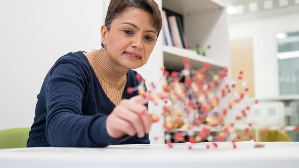 a woman pointing at a molecule model