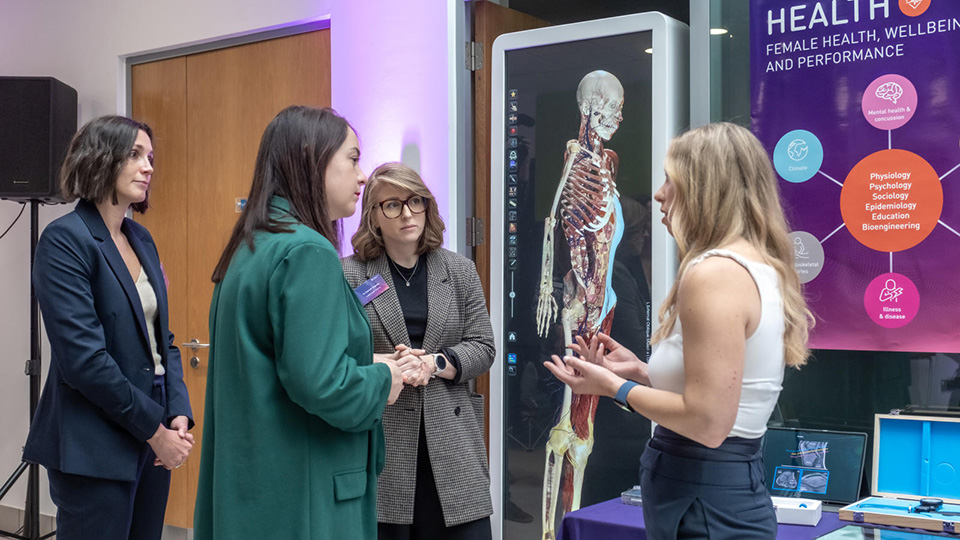 A group of people standing in front of a picture of a skeleton in discussion
