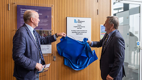 two men holding a blue cloth unveiling a plaque