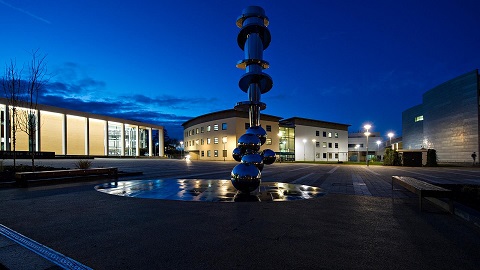 A picture of the Shirley Pearce square at Loughborough University taken at night. The National Centre for Sport and Exercise Medicine is on the left and the Sir John Beckwith Building is on the right.