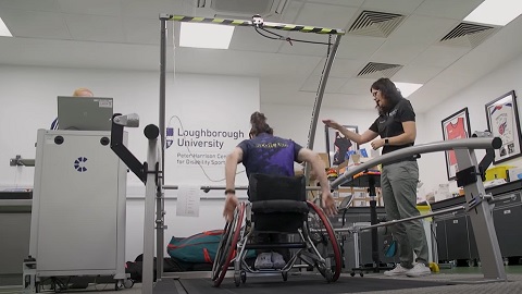 A wheelchair athlete is testing a wheelchair on a treadmill observed by a Loughborough sport scientist