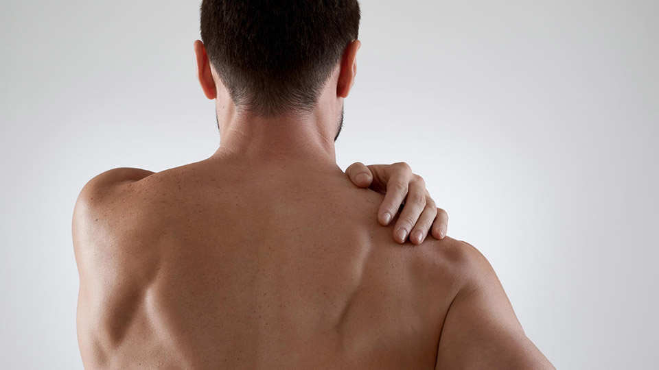 male holding an aching shoulder