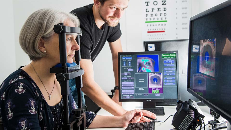 A lady sitting looking at a computer monitor with eye tracking functionality