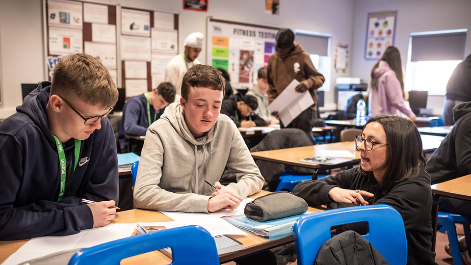 Student teacher helping two pupils during lesson
