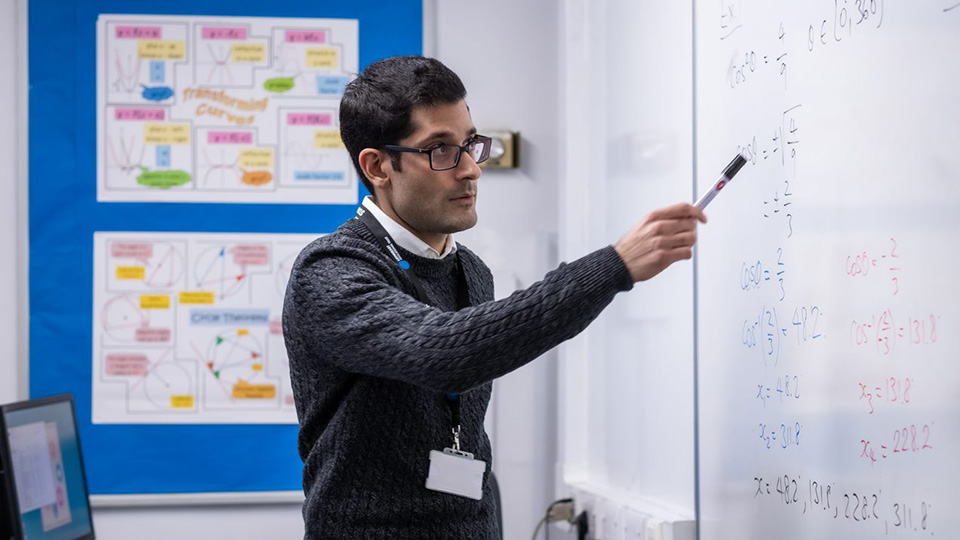 Student teacher pointing at white board