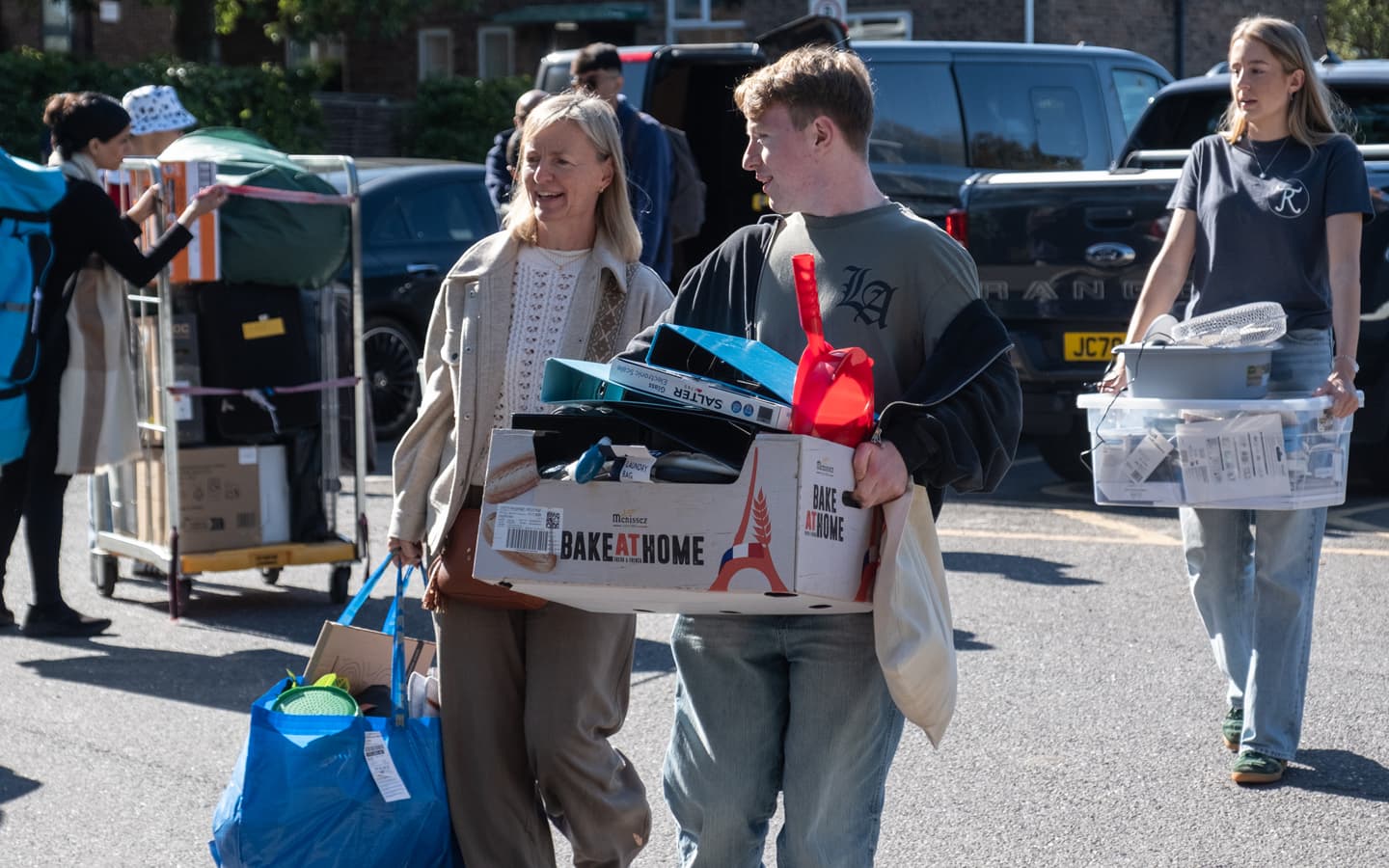 a mother and son arriving to their hall carrying their belongings