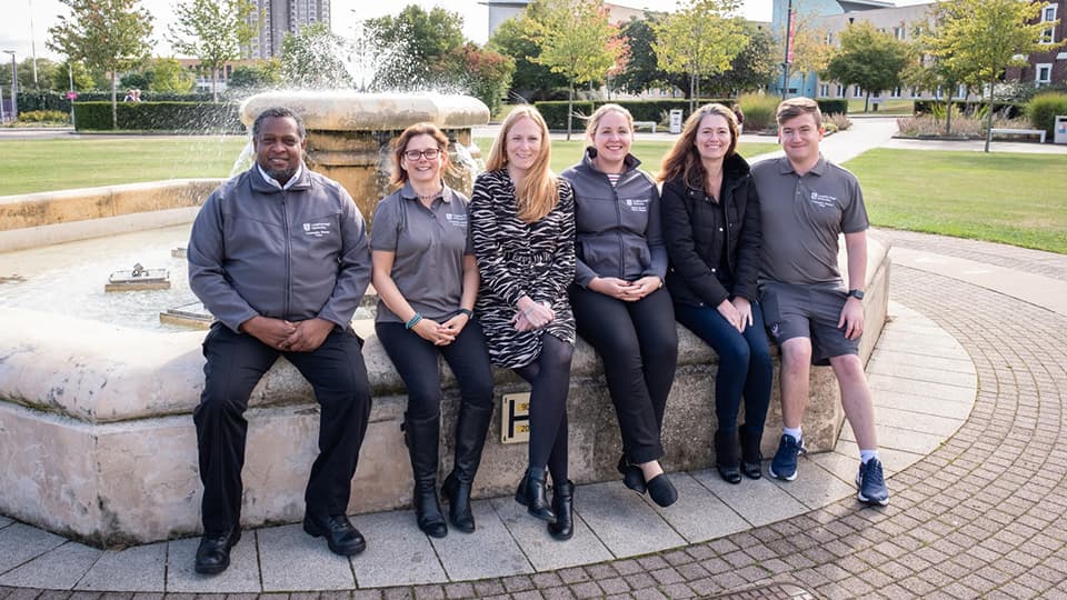 The community warden team sitting on the fountain outside the Hazlerigg buildings