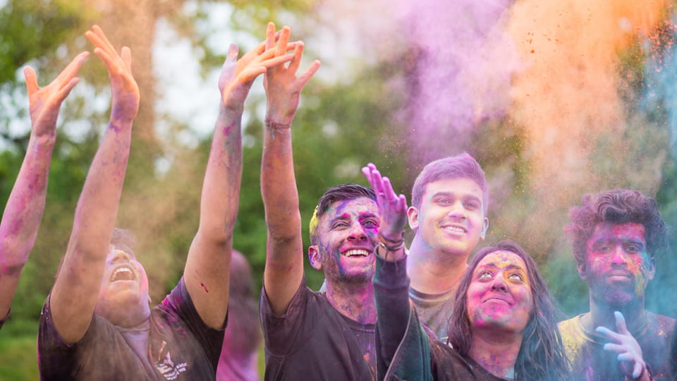 Students taking part in the Holi colour festival throwing powder paint into the air