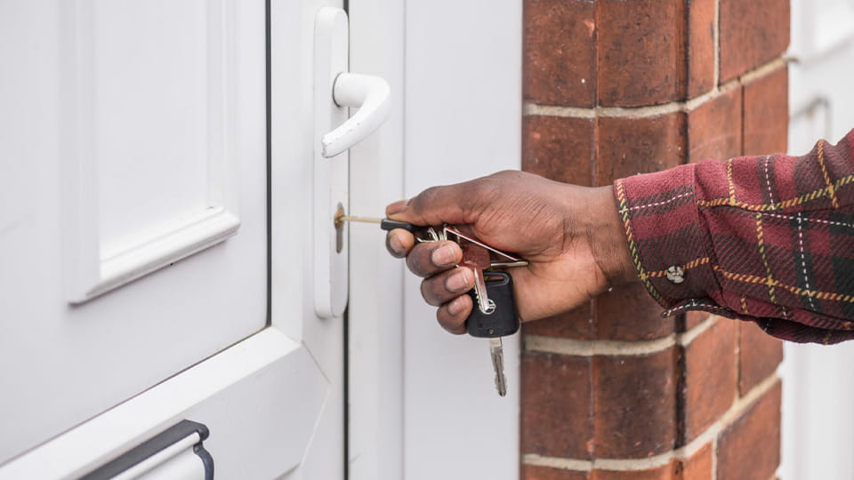 A student holds keys and unlocks a house door