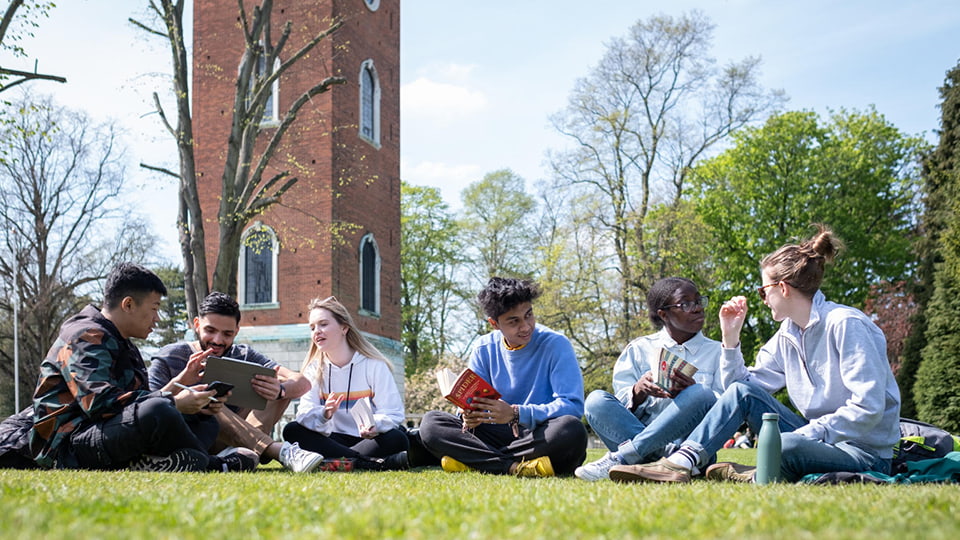 Students sat chatting together on the grass in Queen's park