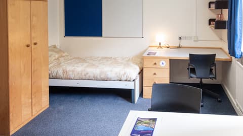 One of the beds in a twin room with a desk at the bottom of the bed