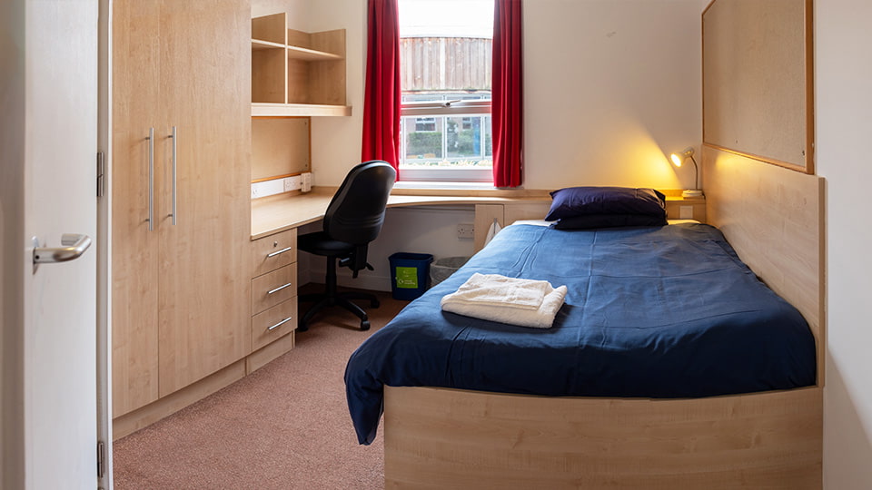 Modern and sophisticated student accommodation in Elvyn Richards catered halls of residence. Large 4ft bed with spacious study desk, wardrobe and shelving.