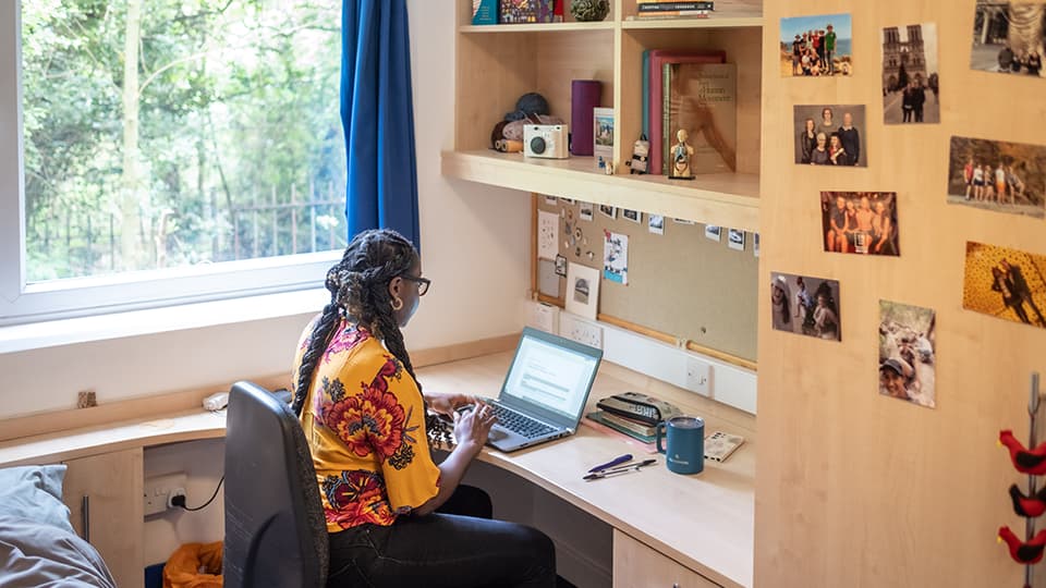 Student sat working at their spacious study desk at their room in John Phillips Loughborough student accommodation
