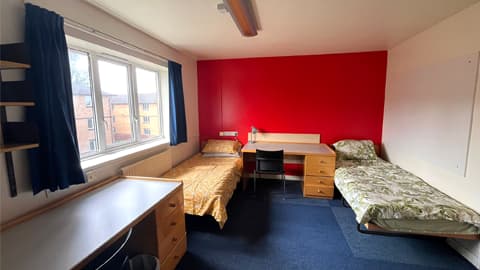 2 single beds and 2 desks in one room with an en-suite bathroom