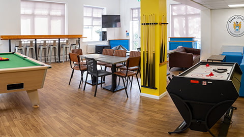 Fully refurbished common room in David Collett student accommodation at Loughborough University, with a pool table, table football, TV, beanbags, chairs and tables.